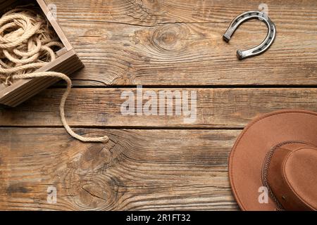 Cowboyhut, Lasso und Hufeisen auf Holzhintergrund Stockfoto