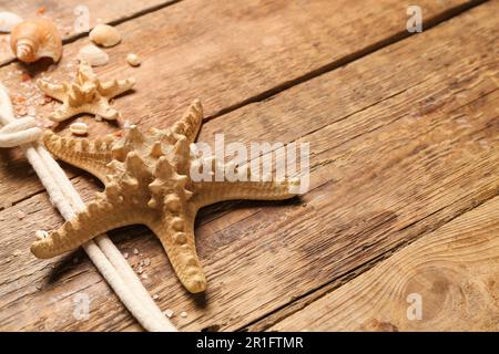 Muscheln und Seesterne mit Seil auf braunem Holzhintergrund Stockfoto