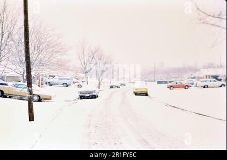 Autos, die während eines Wintersturms auf der Straße und in Auffahrten geparkt haben, ca. 1977 Stockfoto