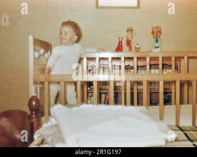 Ein kleiner Junge, ein Kleinkind, steht in einem Kinderbett. 1950-1955 Stockfoto