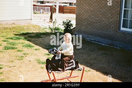 Kleinkind, das auf einem Schaukelpferd in seinem Garten sitzt. 1958 Stockfoto