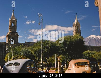 Autos parken vor der Basilika Kathedrale von Arequipa („Basílica Catedral“, auf Spanisch) auf der „Plaza de Armas“ der Stadt Arequipa, Provinz Arequipa, Peru Ca. 1955-1959 Stockfoto