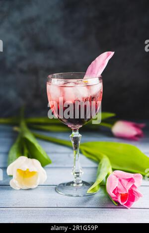 Rosa Cocktail mit Champagner oder Prosecco und Eis in Kristallweinglas und weißen Tulpen Stockfoto