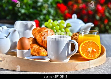 Frühstück serviert mit Kaffee, Orangensaft, Croissants, Müsli und Obst im Garten Stockfoto