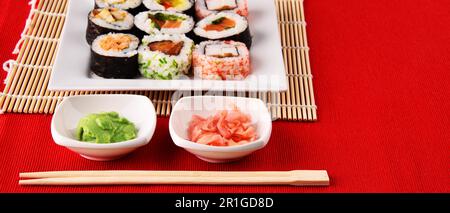 Zusammensetzung mit sortierten Sushi Rollen und Schalen von Gewürzen Stockfoto