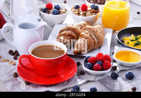 Frühstück mit Kaffee, Orangensaft, Croissants, Ei, Müsli und Obst. Ausgewogene Ernährung Stockfoto