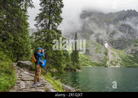 Ein junger Mann macht ein Foto vom See Morskie Oko in den Tatra-Bergen in Polen Stockfoto