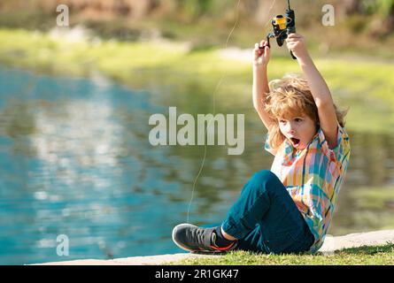 Ein Fischerkind steht mit einer Angelrute im Fluss und fängt Fische. Stockfoto