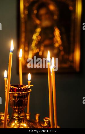 Auf dem Altar vor der Ikone in der dunklen Kirche brennen die Grabkerzen Stockfoto