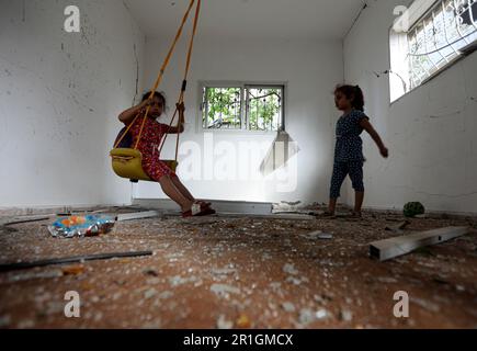 14. Mai 2023: Gaza, Palästina. 14. Mai 2023 Palästinensische Kinder spielen mit einer improvisierten Schaukel in einem Zimmer eines Hauses, das durch israelische Luftangriffe in Deir al-Balah im zentralen Gazastreifen beschädigt wurde. Am späten Samstag wurde eine Waffenruhe vereinbart, um den jüngsten grenzüberschreitenden Feueraustausch zwischen israelischen Streitkräften und palästinensischen Gruppierungen zu beenden, bei dem 33 Palästinenser in Gaza und 2 Menschen in Israel ihr Leben verloren haben (Kreditbild: © Yousef Mohammed/IMAGESLIVE via ZUMA Press Wire), NUR REDAKTIONELLE VERWENDUNG! Nicht für den kommerziellen GEBRAUCH! Stockfoto