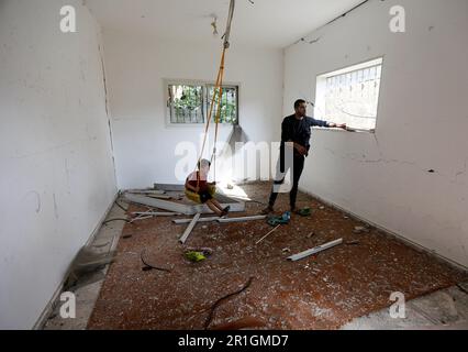 14. Mai 2023: Gaza, Palästina. 14. Mai 2023 Palästinensische Kinder spielen mit einer improvisierten Schaukel in einem Zimmer eines Hauses, das durch israelische Luftangriffe in Deir al-Balah im zentralen Gazastreifen beschädigt wurde. Am späten Samstag wurde eine Waffenruhe vereinbart, um den jüngsten grenzüberschreitenden Feueraustausch zwischen israelischen Streitkräften und palästinensischen Gruppierungen zu beenden, bei dem 33 Palästinenser in Gaza und 2 Menschen in Israel ihr Leben verloren haben (Kreditbild: © Yousef Mohammed/IMAGESLIVE via ZUMA Press Wire), NUR REDAKTIONELLE VERWENDUNG! Nicht für den kommerziellen GEBRAUCH! Stockfoto