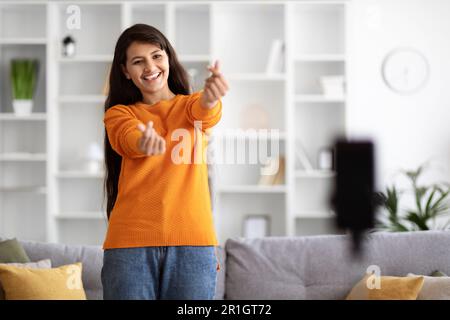 Smartphone nimmt östliche Frau Influencer auf, die zu Hause tanzt Stockfoto