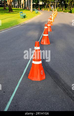 Reihe orange fluoreszierender, reflektierender Verkehrskegel auf der Straße. Stockfoto