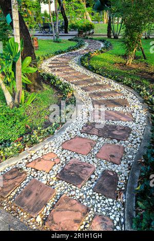 Gasse, Fußgängerweg entlang des Baumes im tropischen Garten. Stockfoto