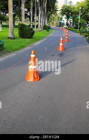 Reihe orange fluoreszierender, reflektierender Verkehrskegel auf der Straße. Stockfoto