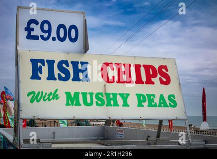 Ein großes Schild, auf dem Fish and Chips am Brighton Beach, East Sussex, Großbritannien, beworben wird. Fish and Chips ist ein nationales Gericht im Vereinigten Königreich und wird immer mit dem in Verbindung gebracht Stockfoto