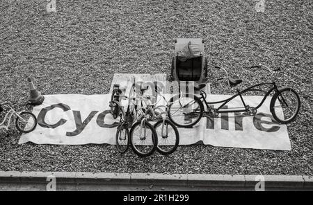 Ein großes Schild mit der Aufschrift „Fahrradverleih“ und verschiedene Fahrräder zum Verleih am Strand in Brighton, East Sussex, Großbritannien. Zu den Fahrrädern gehören ein Tandem und ein Bi für Kinder Stockfoto