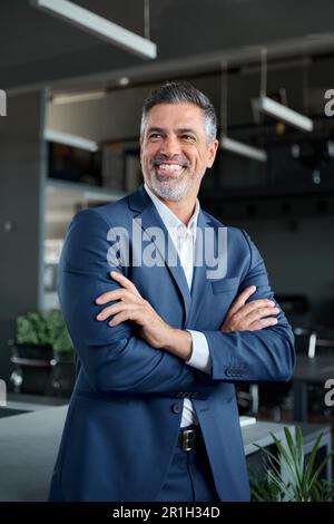 Glücklicher Geschäftsmann mittleren Alters, der im Büro steht, vertikales Porträt. Stockfoto