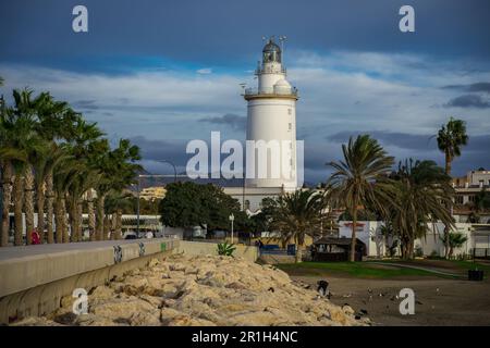 Málaga, Spanien - Nov. 25 2022: La Farola de Málaga - der weiße Leuchtturm von Málaga am Strand, umgeben von Palmen bei Tageslicht Stockfoto