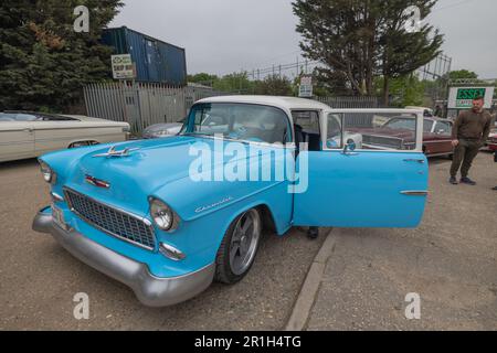 Rayleigh, Großbritannien. Mai 2023. Ein hellblauer 1955er Chevrolet Bel Air mit weißem Dach und modernen Leichtmetallrädern parkt bei einer Oldtimer-Versammlung in Rayleigh, Essex, bei geöffneter Fahrertür. Andere Oldtimer und Beschilderungen sind im Hintergrund zu sehen, einschließlich „KEIN PARKEN VOR DEN TOREN“. Farm Fresh Garage Truck und amerikanische Fahrzeuge werden gezeigt. Penelope Barritt/Alamy Live News Stockfoto