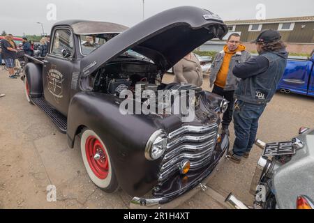 Rayleigh, Großbritannien. Mai 2023. Ein restaurierter schwarzer Pickup-Truck mit roten Felgen und Whitewall-Reifen, die Motorhaube ist offen, um den Motor zu enthüllen. Er wird bei einem Oldtimer-Treffen in Rayleigh, Essex, ausgestellt. Das Logo lautet „L.A. Speed Shop“. Zuschauer beobachten und diskutieren das Fahrzeug unter anderen Oldtimern. Farm Fresh Garage Truck und amerikanische Fahrzeuge werden gezeigt. Penelope Barritt/Alamy Live News Stockfoto