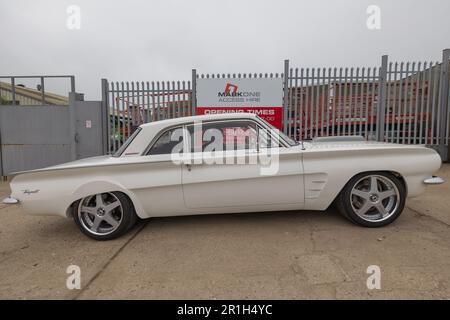 Rayleigh, Großbritannien. Mai 2023. Ein restauriertes, weißes zweitüriges Super Sport Coupé mit kundenspezifischen Leichtmetallfelgen, das vor dem Marcone Appliance Parts Center in Rayleigh, Essex, geparkt ist. Die Szene fängt das Styling der Automobile Mitte des Jahrhunderts vor einem utilitaristischen Hintergrund der britischen Industrie ein. Farm Fresh Garage Truck und amerikanische Fahrzeuge werden gezeigt. Penelope Barritt/Alamy Live News Stockfoto