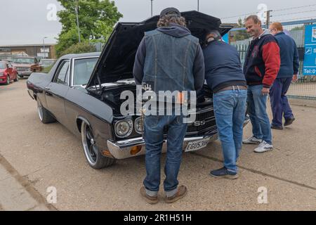 Rayleigh, Großbritannien. Mai 2023. Vier Männer inspizieren den Motor eines schwarzen Chevrolet El Camino SS mit Chromakzenten und kundenspezifischen Rädern, der bei einem Rayleigh-Autotreffen geparkt ist. Die offene Kapuze und die Denim-Weste sind ein lässiges, von Enthusiasten geleitetes Treffen. Farm Fresh Garage Truck und amerikanische Fahrzeuge werden gezeigt. Penelope Barritt/Alamy Live News Stockfoto