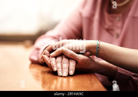 Alles wird gut. Eine Krankenschwester, die eine ältere Frau behaglich an den Händen hält. Stockfoto