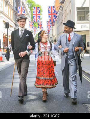 London, Großbritannien. 14. Mai 2023. Zwei Männer gehen mit einer jungen Dame in polnischen Folklorekleidern entlang der Jermyn Street. Auf dem jährlichen Grand Flaneur Walk sehen Sie Kerle und Kapseln, Dandys und Quaintrelle in makelloser Schneiderei und stilvoller Flanning und unnötiges Herumsäen rund um St James' und die umliegenden Gegenden von London. Der Spaziergang beginnt immer an der Statue des geselligen Dandy Beau Brummell und führt langsam durch die Gegend. Kredit: Imageplotter/Alamy Live News Stockfoto