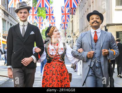 London, Großbritannien. 14. Mai 2023. Zwei Männer gehen mit einer jungen Dame in polnischen Folklorekleidern entlang der Jermyn Street. Auf dem jährlichen Grand Flaneur Walk sehen Sie Kerle und Kapseln, Dandys und Quaintrelle in makelloser Schneiderei und stilvoller Flanning und unnötiges Herumsäen rund um St James' und die umliegenden Gegenden von London. Der Spaziergang beginnt immer an der Statue des geselligen Dandy Beau Brummell und führt langsam durch die Gegend. Kredit: Imageplotter/Alamy Live News Stockfoto