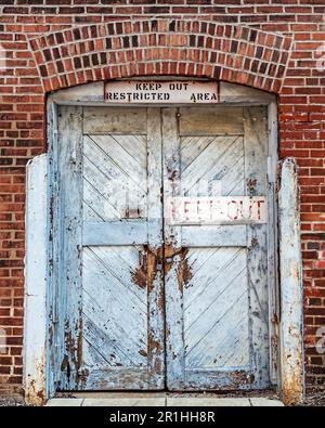 Hintergrundbild von alten Lagertüren in einer Ziegelwand mit einem „Hep-out“-Schild Stockfoto
