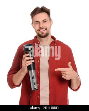 Ein lächelnder Mann zeigt auf einen Sous-Vide-Herd vor weißem Hintergrund Stockfoto