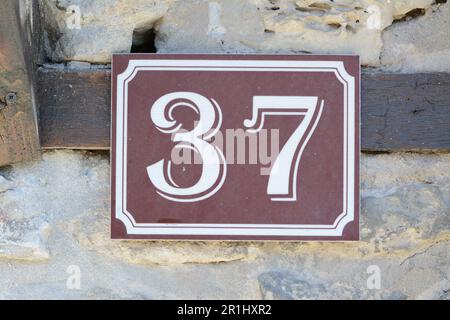 Nummernschild mit Haus Nr. 37 an einer Steinmauer draußen, schließen Stockfoto