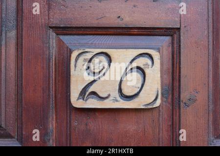 Nummernschild mit Hausnummer 26 auf Holztür, schließen Stockfoto