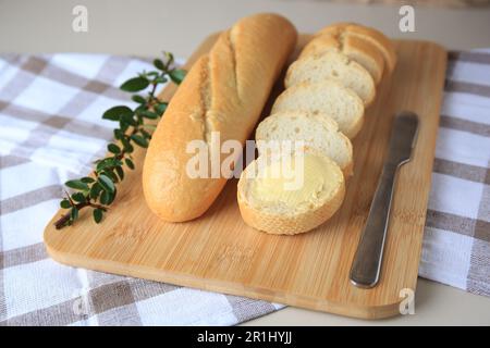 Ganze und geschnittene Baguettes mit frischer Butter auf dem Tisch Stockfoto