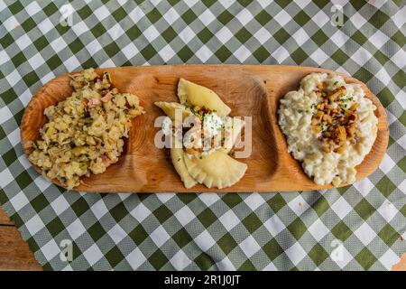 Teller mit traditionellen slowakischen Gerichten - Kapustove Strapacky (Knödel mit Kohl), bryndzove Pirohy (Pirogi mit bryndza Schafskäse) und bryndzove h Stockfoto