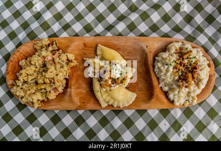 Teller mit traditionellen slowakischen Gerichten - Kapustove Strapacky (Knödel mit Kohl), bryndzove Pirohy (Pirogi mit bryndza Schafskäse) und bryndzove h Stockfoto