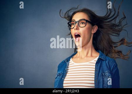 Das ist erstaunlich. Eine glückliche junge Frau, die im Studio Luft ins Gesicht geblasen hat. Stockfoto