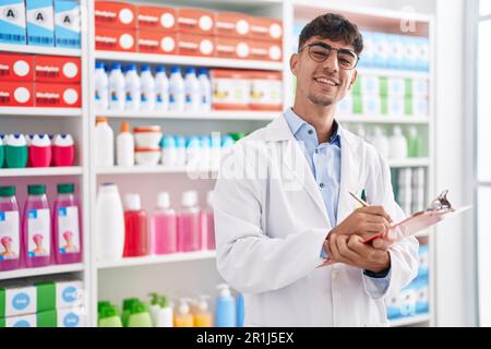 Junger hispanischer Apotheker, der auf einem Dokument in der Apotheke schreibt Stockfoto