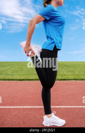 Sportlerin wärmt sich vor dem Laufen auf, Läuferin auf der Laufbahn. Stockfoto