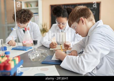 Seitenansicht des Schuljungen im Wissenschaftsunterricht mit Kindergruppe, Kopierraum Stockfoto