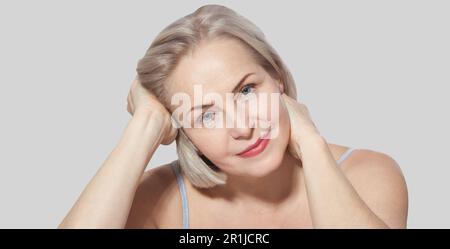 Eine wunderschöne blonde Frau mittleren Alters zeigt ihr perfekt gepflegtes Gesicht. Makrofläche. Realistische Bilder mit eigenen Unvollkommenheiten. Stockfoto