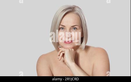 Eine wunderschöne blonde Frau mittleren Alters zeigt ihr perfekt gepflegtes Gesicht. Makrofläche. Realistische Bilder mit eigenen Unvollkommenheiten. Stockfoto