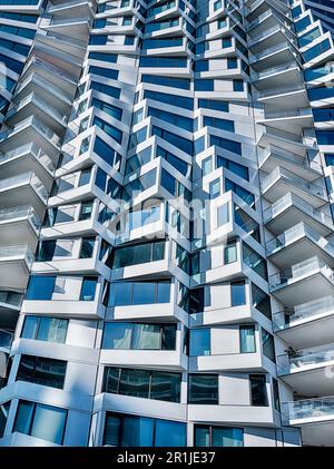 Sonnenlicht unterstreicht den Kontrast zwischen Licht und Schatten auf der Außenseite eines modernen Appartementgebäudes. Stockfoto