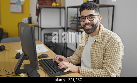 Junger hispanischer Mann, der im Büro mit einem Computer arbeitet Stockfoto