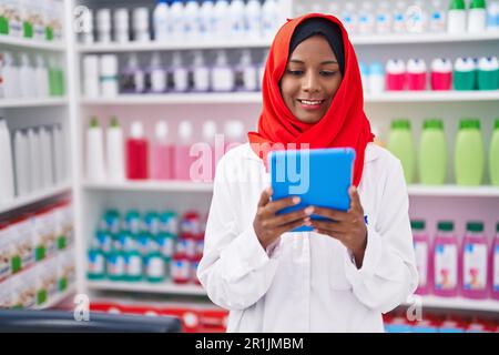 Junge, schöne Apothekerin, die Touchpad benutzt und in der Apotheke arbeitet Stockfoto