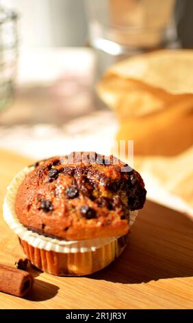 Vanille-Schokoladenkuchen in einer Wellform. Es gibt Zimtstangen auf dem Tisch, eine silberne Kaffeemaschine und einen Korb mit Zucker. Stockfoto