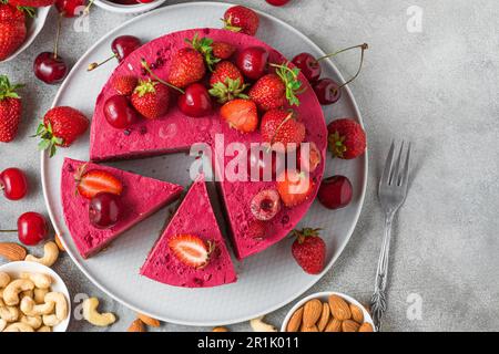 Rohe vegane Erdbeeren- und Kirschkashewkuchen mit frischen Beeren und Nüssen. Vegetarisches Dessert. Draufsicht Stockfoto