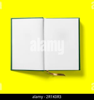 Back-to-School-Konzept, Hardcover dunkelgrünes Buch erste Seite offen isoliert auf Gelb. Stockfoto
