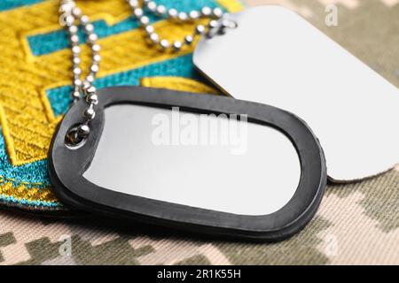 Militärische ID-Tags und ukrainischer Patch auf Pixeltarnung, Nahaufnahme Stockfoto